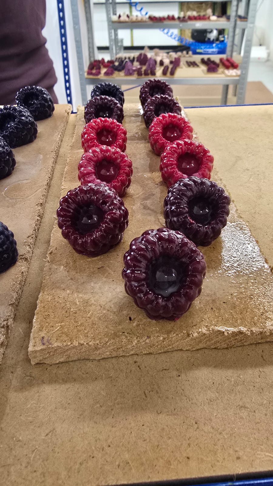 Bougies en cire en forme de framboises après vernissage, surface lisse et brillante